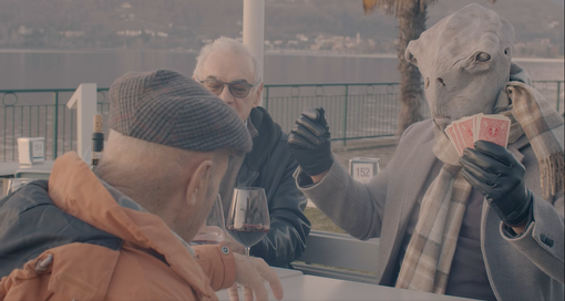 La partita a carte tra cittadini di Ranco e un alieno in riva al lago Maggiore (foto tratta dal video della Pro Loco) La partita a carte tra cittadini di Ranco e un alieno in riva al lago Maggiore (foto tratta dal video della Pro Loco)