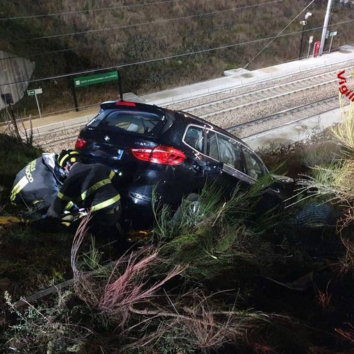 FOTO. Perde il controllo dell'auto e finisce in bilico sulla ferrovia: per recuperarlo servono i vigili del fuoco