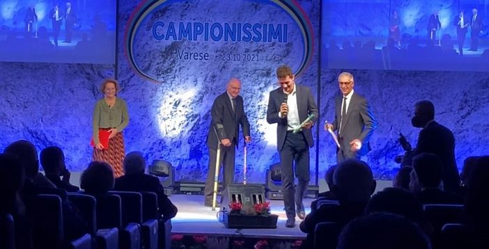 Uno dei momenti più intensi dell'edizione 2021 di Campionissimi: Filippo Tortu, seguito dallo sguardo affettuoso di Livio Berruti (sul palco), consegna il testimone dell'ultima frazione della staffetta d'oro olimpica ad Alfredo Ambrosetti