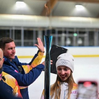 La torcia olimpica torna al palaghiaccio di Varese: in foto è sostenuta dalla pattinatrice varesina Ginevra Negrello